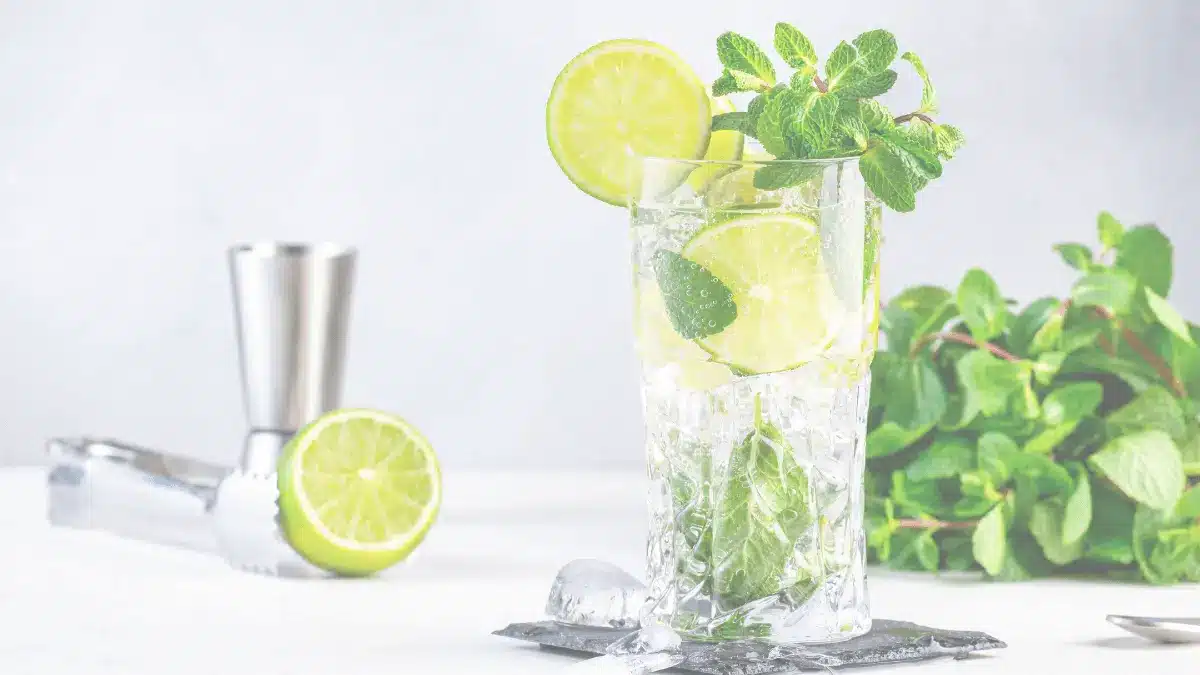 Glass of caipirinha cocktail with lime wedges and ice on a rustic table